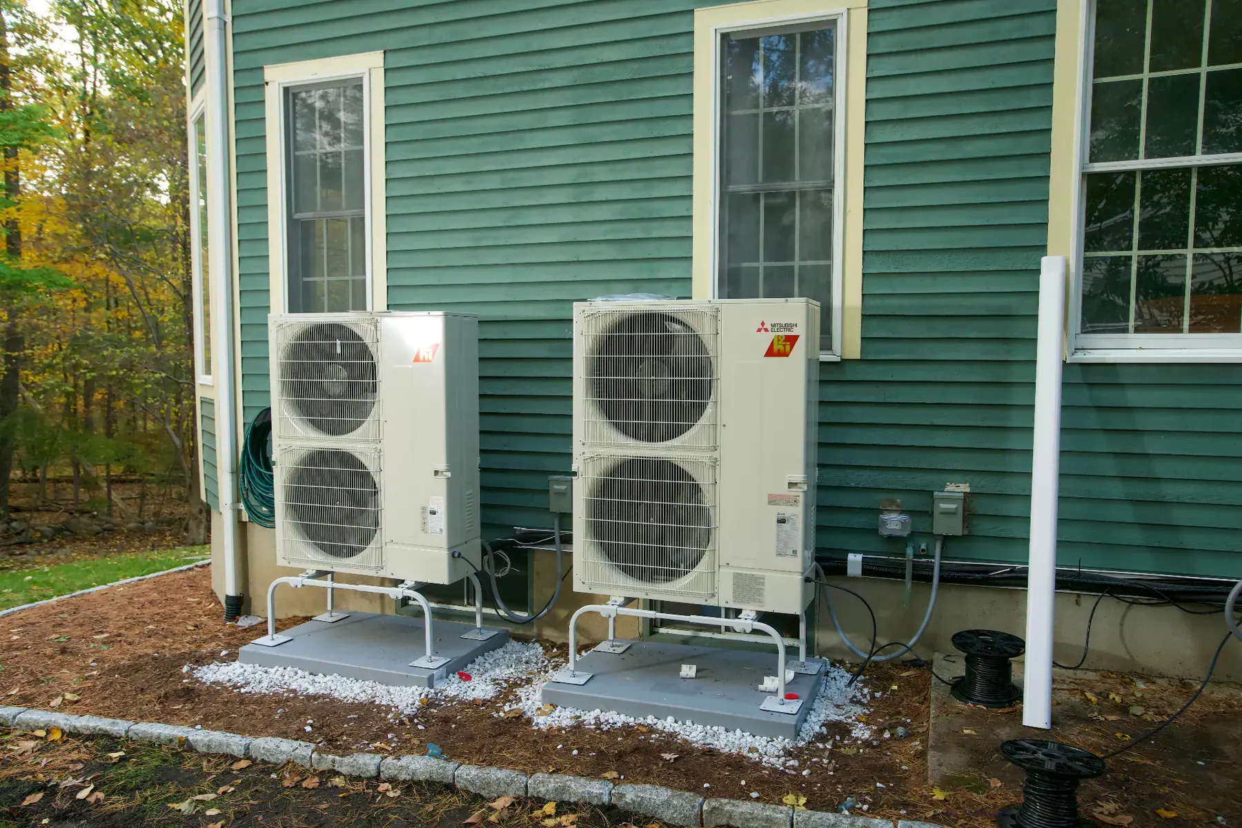 Two Mitsubishi Electric heat pump outdoor units installed on a Massachusetts home