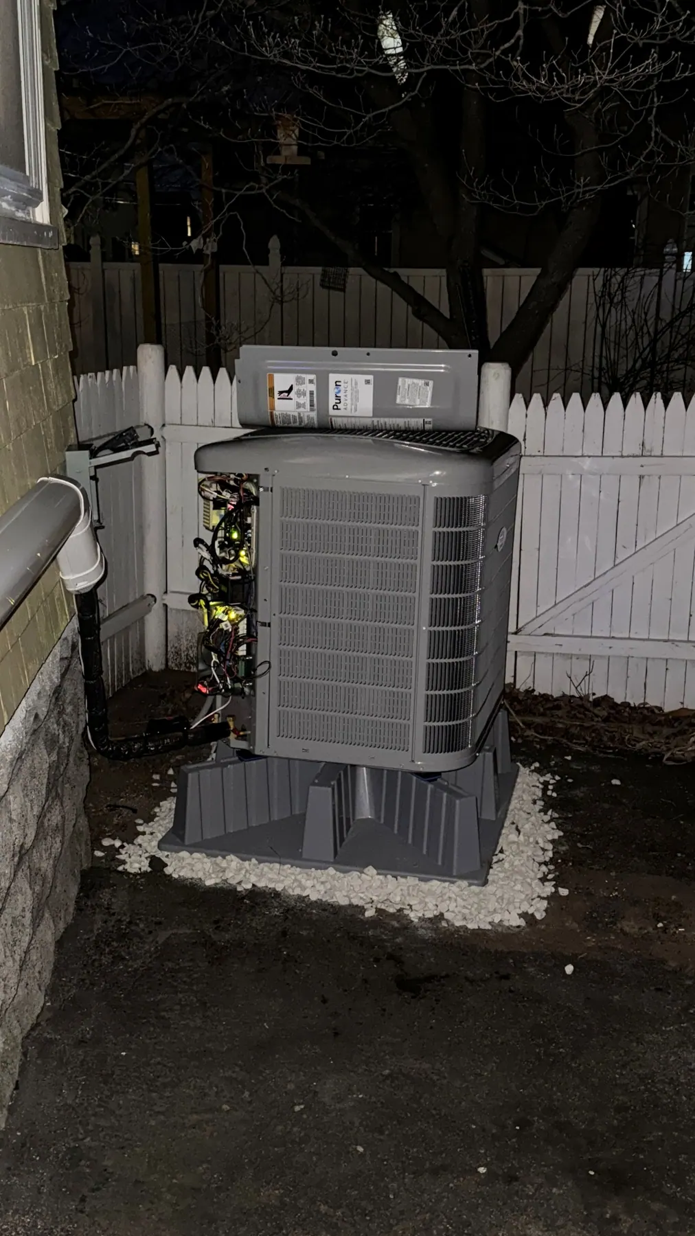Heat pump condenser install completed on a raised pad at night